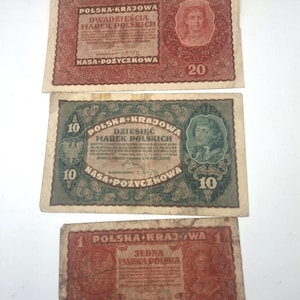 Puede incluir: Tres billetes polacos antiguos con bordes decorativos y retratos. El billete superior es rojo con el texto 'DWADZIEŚCIA MAREK POLSKICH', el central es verde con 'DZIESIĘĆ MAREK POLSKICH' y el inferior es rojo con 'JEDNA MARKA POLSKA'.