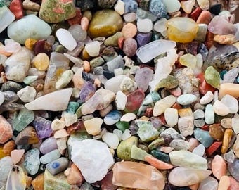 以下が含まれることがあります： 様々な色合いの、滑らかで磨かれた石のクローズアップ画像。石は様々な形と大きさで、ランダムなパターンで配置されています。石は天然石と研磨された石の混合です。