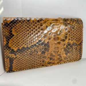 May include: A brown and black snakeskin wallet with a textured surface.