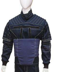May include: A dark blue jumpsuit with black accents and a padded chest piece. The jumpsuit has a high collar and long sleeves.