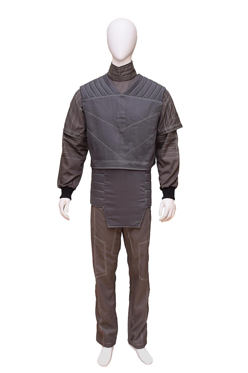 May include: A grey jumpsuit with a padded vest. The vest has a quilted design and a high collar. The jumpsuit has a straight leg and is made of a durable fabric.