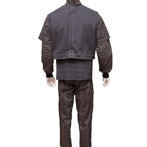 May include: A grey quilted jumpsuit with a high collar and a zip closure. The jumpsuit has a fitted bodice and straight legs. The fabric has a subtle diamond pattern.