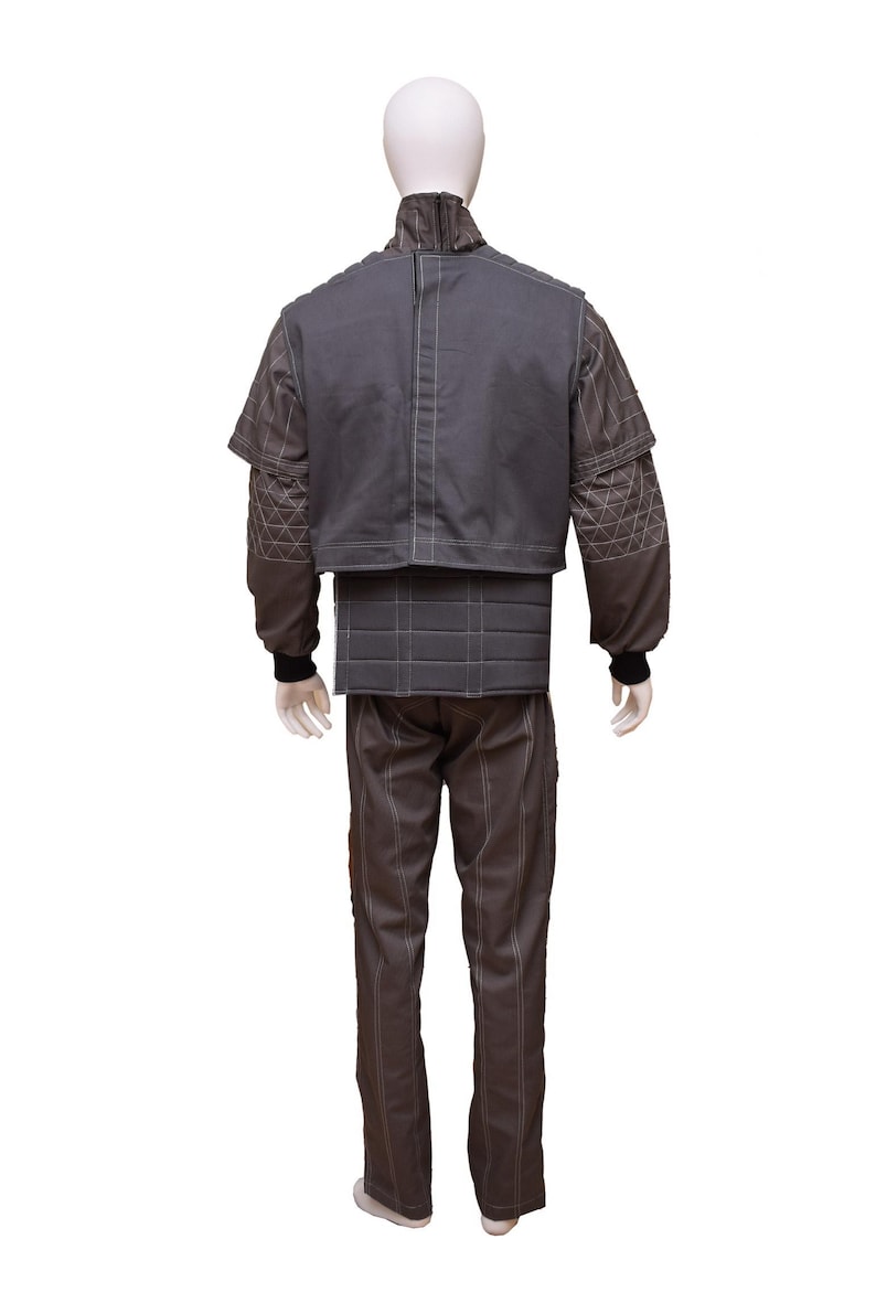 May include: A grey quilted jumpsuit with a high collar and a zip closure. The jumpsuit has a fitted bodice and straight legs. The fabric has a subtle diamond pattern.