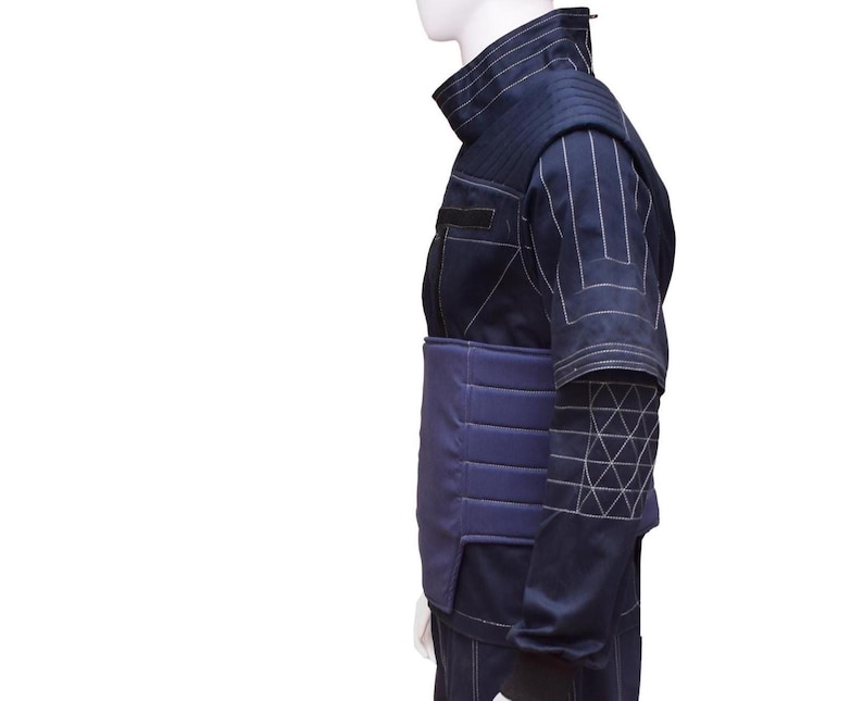 May include: A dark blue jacket with a padded, quilted chest and a geometric pattern on the sleeve. The jacket has a high collar and a zipper closure.