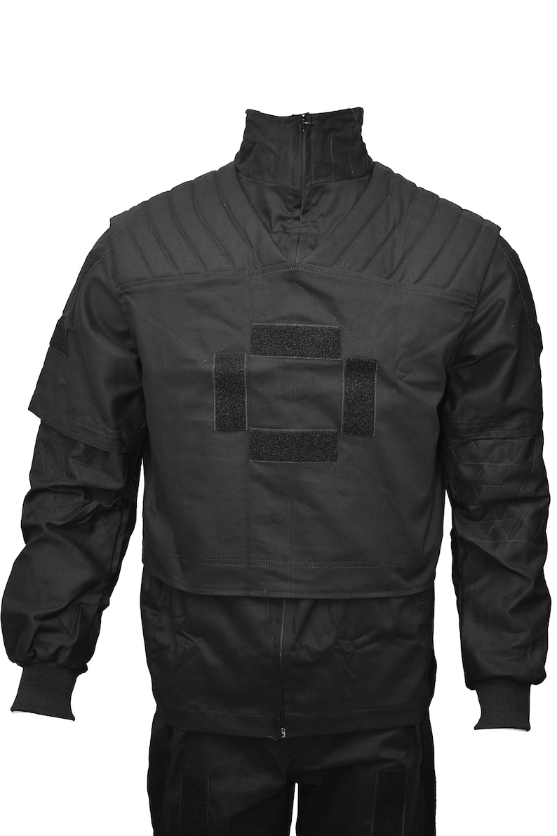 May include: Black tactical jacket with a high collar and zipper closure. The jacket has a large velcro patch on the chest with a cross design.