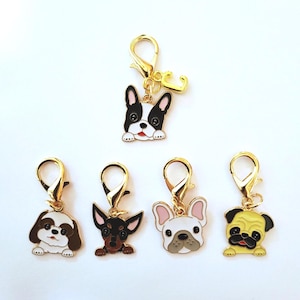 May include: Five dog-themed charms with gold-colored clasps. The charms feature different dog breeds, including a black and white Boston Terrier, a Shih Tzu, a Chihuahua, a French Bulldog, and a Pug. Each charm has a detailed, colorful design.