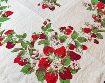 May include: A white fabric tablecloth featuring a repeating pattern of red strawberries, green leaves, and small white flowers. The design is arranged in clusters across the surface, showcasing detailed illustrations of ripe fruit and foliage.