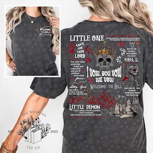 K&ouml;nnte beinhalten: Dunkelgraues T-Shirt mit floralem Muster und dem Text "Welcome to Hell, Little Darling". Die R&uuml;ckseite des Shirts zeigt gotische Texte und Grafiken, darunter ein Sch&auml;del mit Krone, Rosen und die Worte "Little One" und "Little Demon".