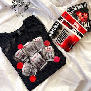 May include: Black t-shirt with a floral pattern and a graphic of jars with book titles and red roses. The books "Corrupt", "Nightfall", and "Fall" by Penelope Douglas are also visible.