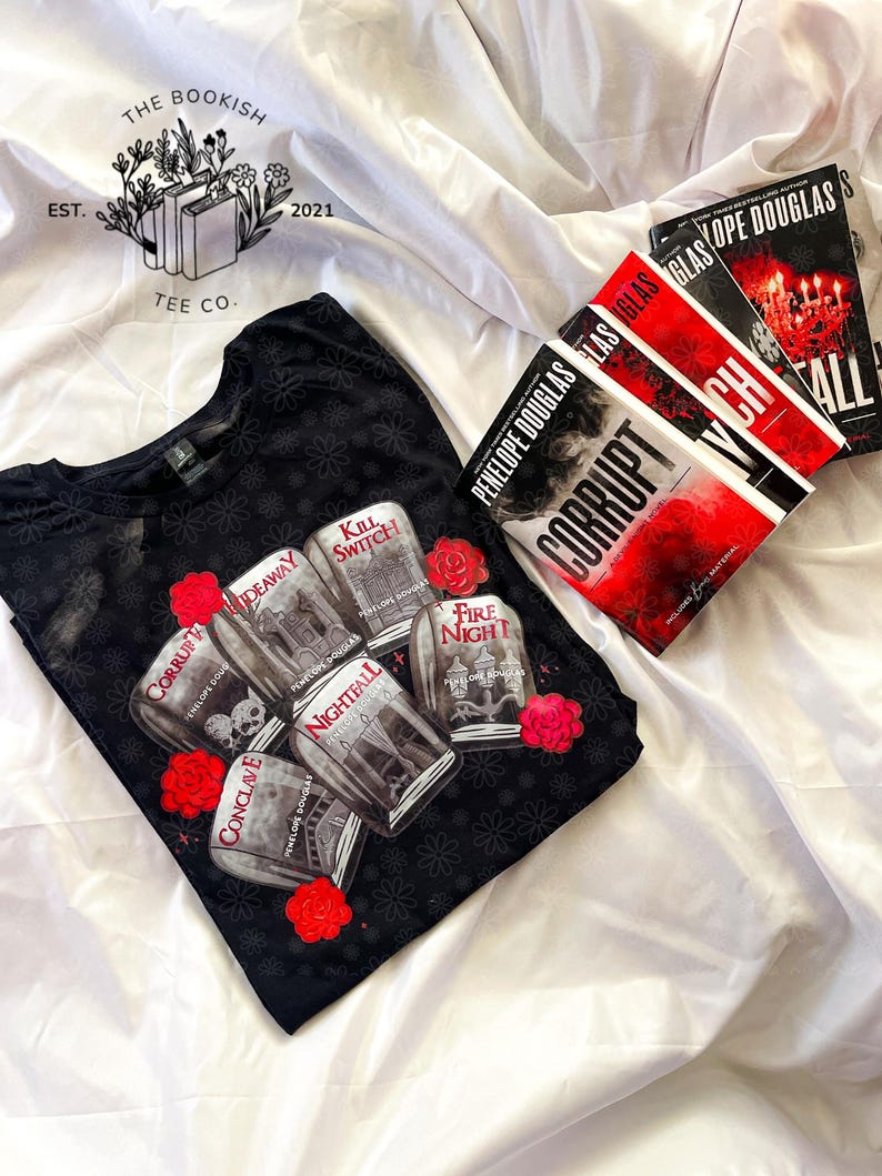 May include: Black t-shirt with a floral pattern and a graphic of jars with book titles and red roses. The books "Corrupt", "Nightfall", and "Fall" by Penelope Douglas are also visible.