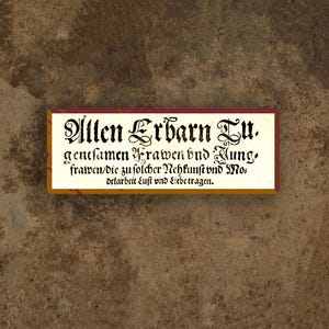 May include: A rectangular sign with ornate black lettering on a cream background. The sign has a dark red border and is set against a textured brown background. The text is in an old-style font.