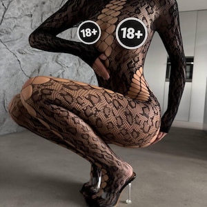 May include: Black fishnet bodysuit with a snake scale pattern. The bodysuit has long sleeves and a high neckline. The image includes two circles with the text "18+". The person is wearing clear platform heels.