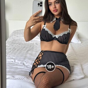May include: Black and white striped lingerie set with a matching tie and white collar. The set includes a bra, skirt, and thigh-high stockings. The skirt features a lace-up design on the side and a white lace trim.