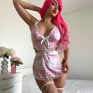 May include: Pink and white gingham lingerie set with a matching apron. The top has a halter neck and a bow detail. The apron has two pockets and a ruffled edge. The model is wearing white fishnet stockings.