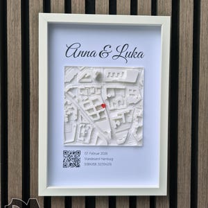 Könnte beinhalten: Ein weiß gerahmter 3D-Stadtplan mit den Namen "Anna & Luka" oben. Der Plan hat eine rote Markierung. Unter dem Plan befinden sich ein QR-Code und Text, alles in einem weißen Rahmen.