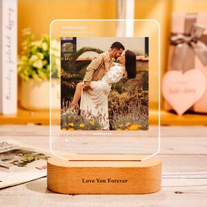 May include: A clear acrylic photo display with a wooden base. The display features a photo of a couple and the text "Love You Forever". The photo is designed to look like a social media post.