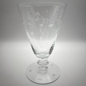 May include: A clear glass goblet with a star-shaped pattern etched into the glass. The goblet has a tall, conical bowl and a short, round stem.