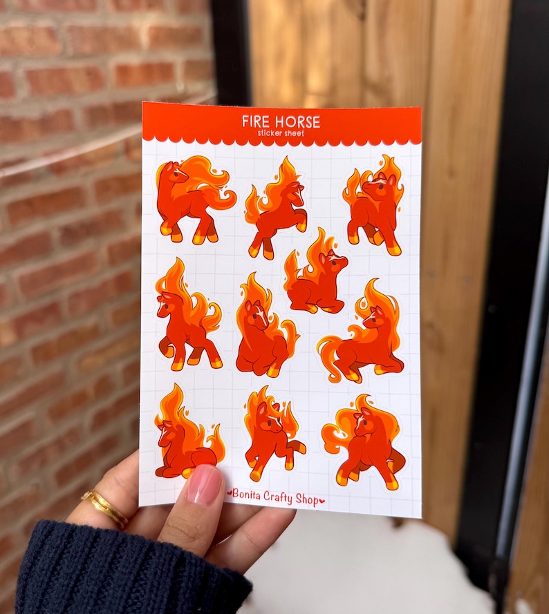 Puede incluir: Una hoja de pegatinas con ilustraciones de caballos de fuego. Los caballos son de color naranja y amarillo, con crines y colas de llama. El texto "FIRE HORSE sticker sheet" est&aacute; en la parte superior. El nombre de la tienda "Bonita Crafty Shop" est&aacute; en la parte inferior.