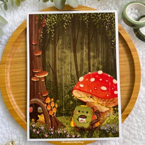May include: A whimsical art print featuring a forest scene with a large red mushroom with white spots. A small, green character with a cup of coffee sits on a bench. The print includes a tree with mushroom accents and the text "aBonitacraftyshop".