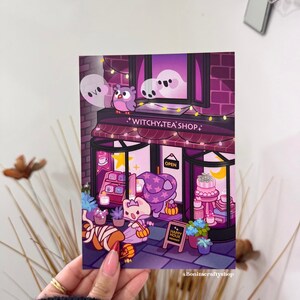 以下が含まれることがあります： 紫とピンクの色合いの、魔女をテーマにしたお茶屋さんの気まぐれなイラスト。お店にはフクロウ、幽霊、魔女の帽子をかぶった猫が登場します。「Witchy Tea Shop」と「Happy Hour」と書かれた看板があります。