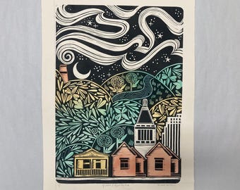 May include: A colorful linocut print depicting a nighttime landscape. The artwork features stylized houses, rolling hills with floral patterns, a crescent moon, stars, and swirling clouds against a black sky. The print is signed and titled.