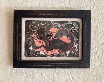 May include: A black and white print of a sleeping fox with pink accents, framed in a black wood frame. The print is titled "Vulpecula" and signed "Nicole Martin".