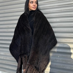 May include: A brown fur shawl with long fringe. The shawl is draped over a person's shoulders.