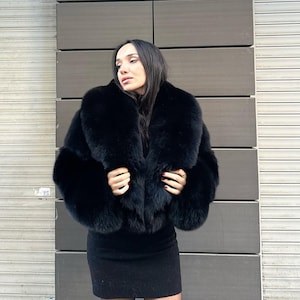 May include: A black fur jacket with a large collar. The jacket is cropped and has a fitted silhouette.