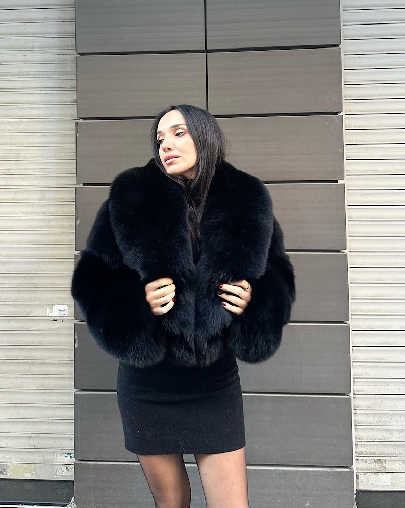 May include: A black fur jacket with a large collar. The jacket is cropped and has a fitted silhouette.