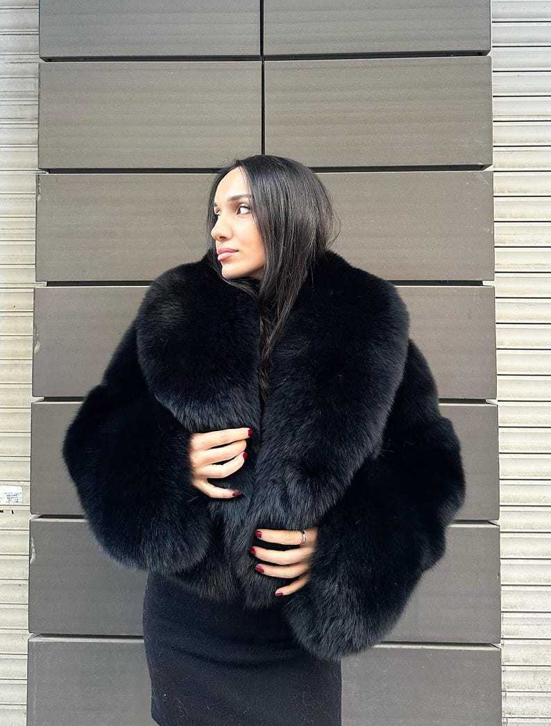 May include: A black fur jacket with a large collar. The jacket is cropped and has a fitted silhouette.