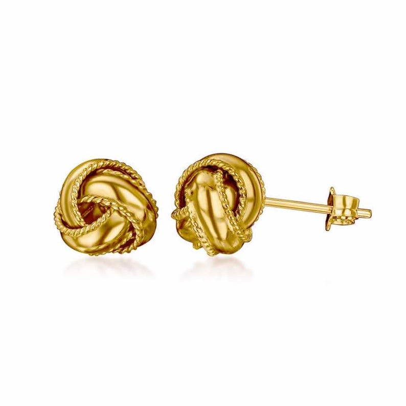 May include: A pair of gold knot-shaped stud earrings. The earrings are made of a smooth, shiny metal and have a simple, elegant design.