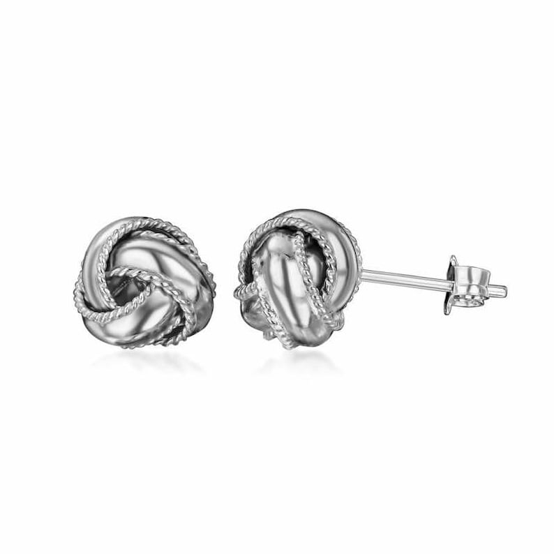 May include: A pair of silver knot-shaped stud earrings. The earrings are made of a smooth, shiny metal and have a simple, elegant design.