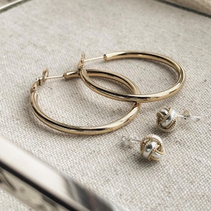 May include: Two pairs of gold hoop earrings and two pairs of silver and gold knot earrings.