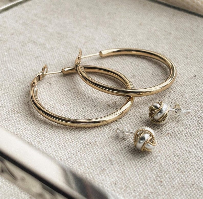 May include: Two pairs of gold hoop earrings and two pairs of silver and gold knot earrings.