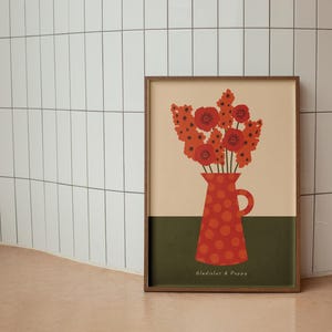 Framed wall art print in red, orange and olive green featuring gladioluses and the poppies in a polka dot vase. There is text below the vase in a hand-written font that lists the flowers.