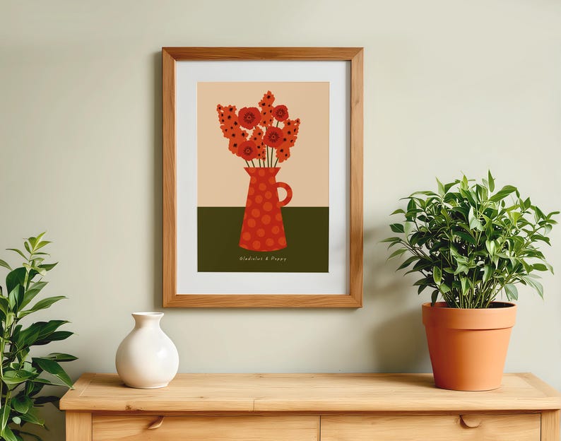 Framed wall art print in red, orange and olive green featuring gladioluses and the poppies in a polka dot vase. There is text below the vase in a hand-written font that lists the flowers.