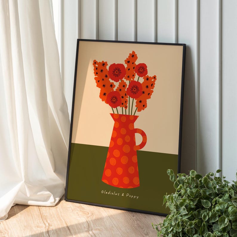 Framed wall art print in red, orange and olive green featuring gladioluses and the poppies in a polka dot vase. There is text below the vase in a hand-written font that lists the flowers.