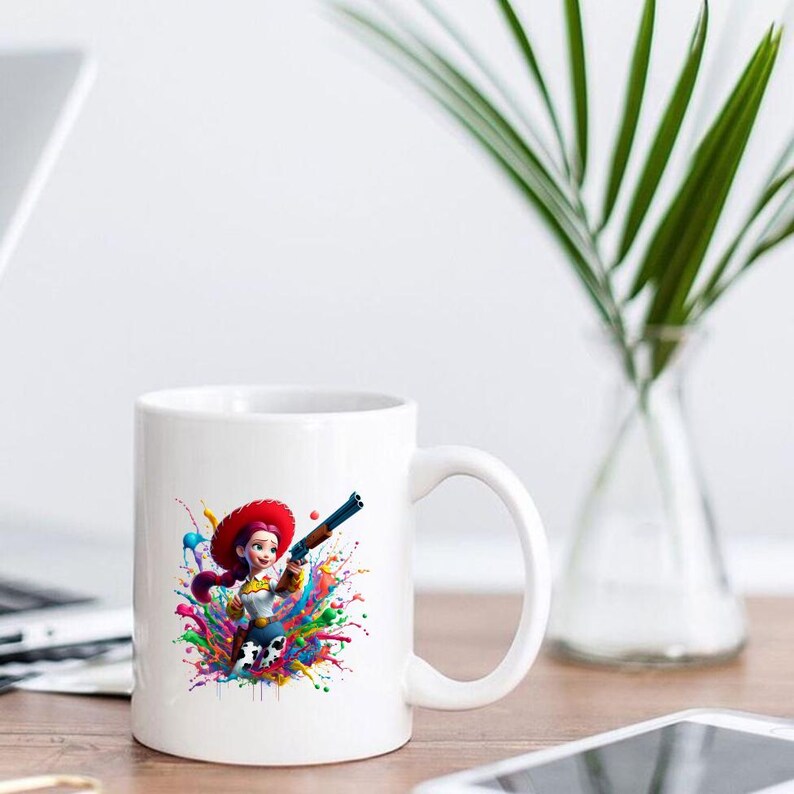 May include: White ceramic mug featuring a colorful illustration of a cowgirl with a red hat and a gun, set against a vibrant splash of paint. The design includes shades of blue, green, yellow, and pink.