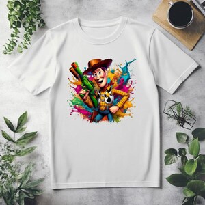 May include: White t-shirt with a colorful paint splatter design featuring Woody from Toy Story holding a green toy gun.