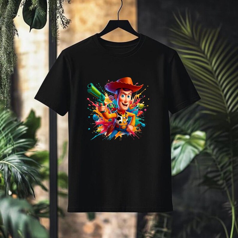 May include: Black t-shirt with a colorful graphic of Woody from Toy Story holding a green gun. The graphic is surrounded by colorful paint splatters.
