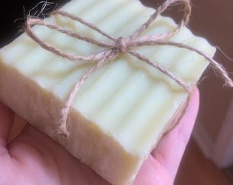 May include: A light green bar of soap wrapped in twine. The soap has a ridged texture and is tied with a bow.