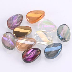 May include: A selection of iridescent, teardrop-shaped beads in shades of purple, gold, orange, and blue. The beads have a glossy finish and are displayed on a white surface. These beads are suitable for jewellery making and craft projects.