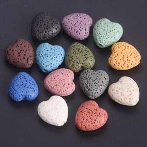 May include: A collection of heart-shaped lava stones in a range of colours, such as black, purple, blue, green, and orange. Each stone has a porous texture. These stones are suitable for jewellery making or aromatherapy.