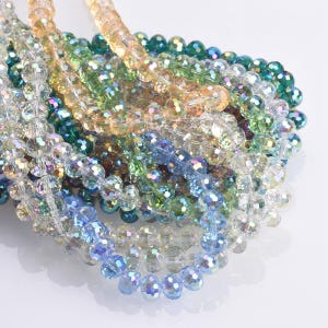May include: Strands of iridescent crystal beads in various colors, including blue, green, yellow, and clear. The beads are faceted, reflecting light and creating a sparkling effect. These beads are suitable for jewelry making and craft projects.