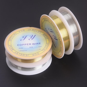 May include: Spools of copper wire in gold and silver colors. The spools have labels that read "COPPER WIRE" and "SPECIAL FOR JEWELRY BEAD". The wire is 0.5 mm in size, perfect for jewelry making.