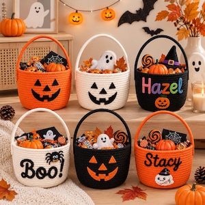 May include: Six round woven rope baskets for Halloween, each featuring a handle and filled with assorted candies and small decorations. Designs include jack-o'-lantern faces, ghosts, spiders, and personalized names like Hazel and Stacy.
