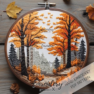 May include: Hand-embroidered autumn forest scene in a wooden hoop. The artwork features trees with orange and yellow leaves, a path, and evergreen trees. The text "Emroidery Studio X" is visible. The design is a PDF pattern.