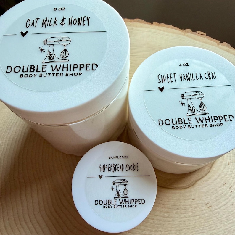 May include: Three round white plastic jars of body butter with white lids. The largest jar is labeled 8 oz Oat Milk & Honey, the medium jar is 4 oz Sweet Vanilla Chai, and the smallest is a sample size Gingerbread Cookie, all with a mixer logo.