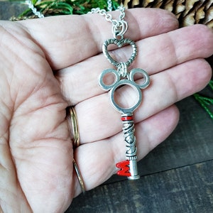 An antique silver key pendant hangs from a silver chain, reminiscent of a Kingdom Hearts keyblade.  Held in an open hand to compare relative size.