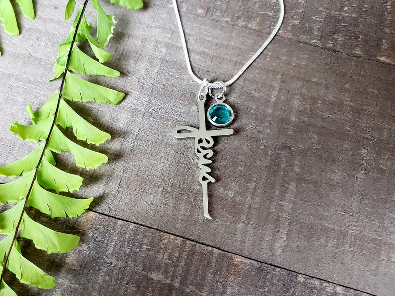 Steel Jesus cross necklace, with a blue zircon birthstone charm.